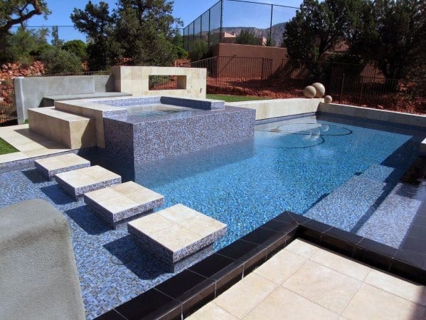 Modern swimming pool with geometric design, mosaic tiles, and floating stone steps.