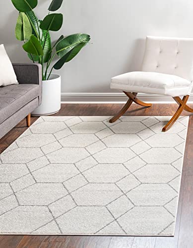 White geometric rug in a cozy living room with a gray sofa, white chair, and potted plant.