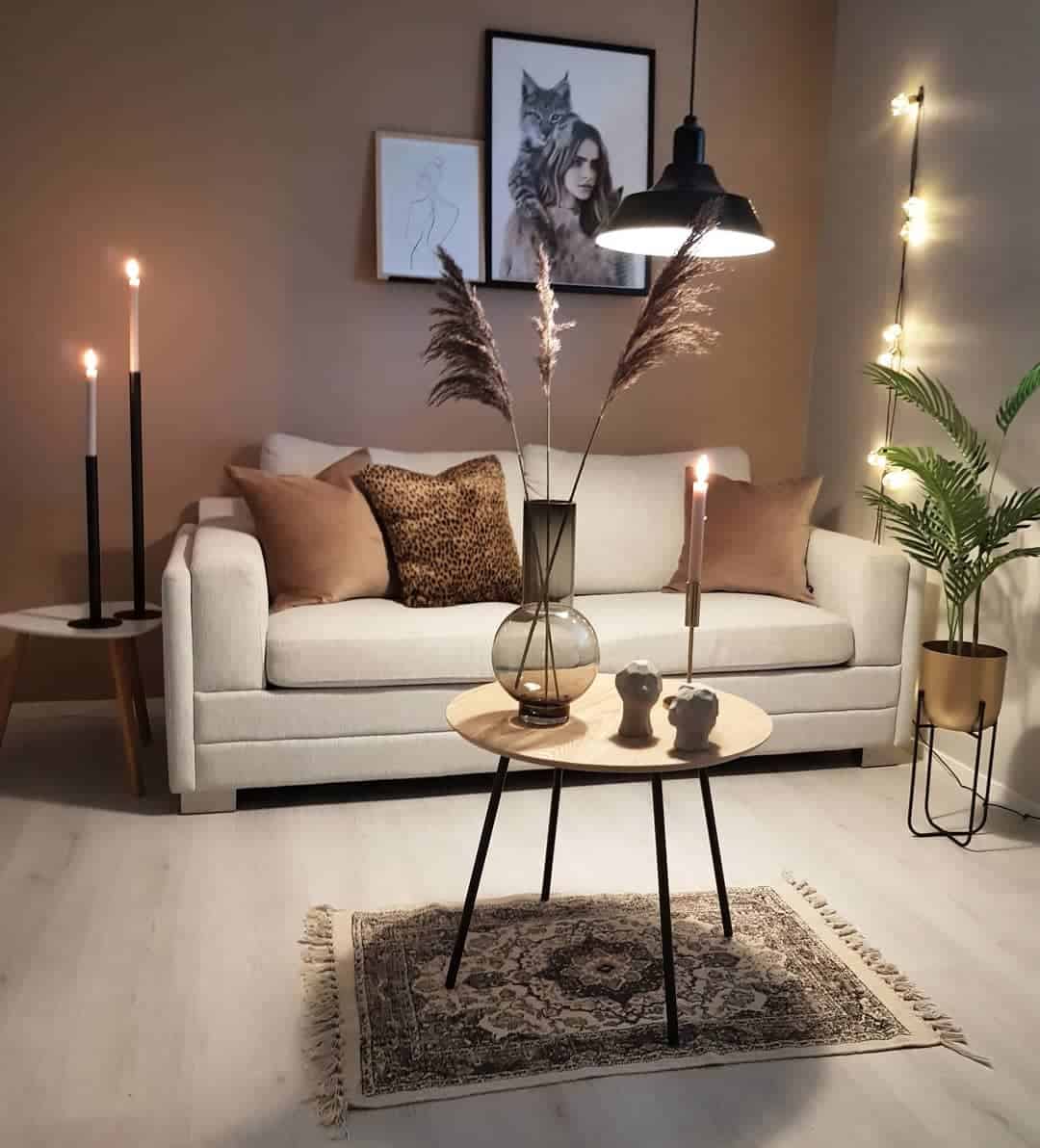 Cozy living room with a brown sofa, modern art, candles, and a small round table on a patterned rug