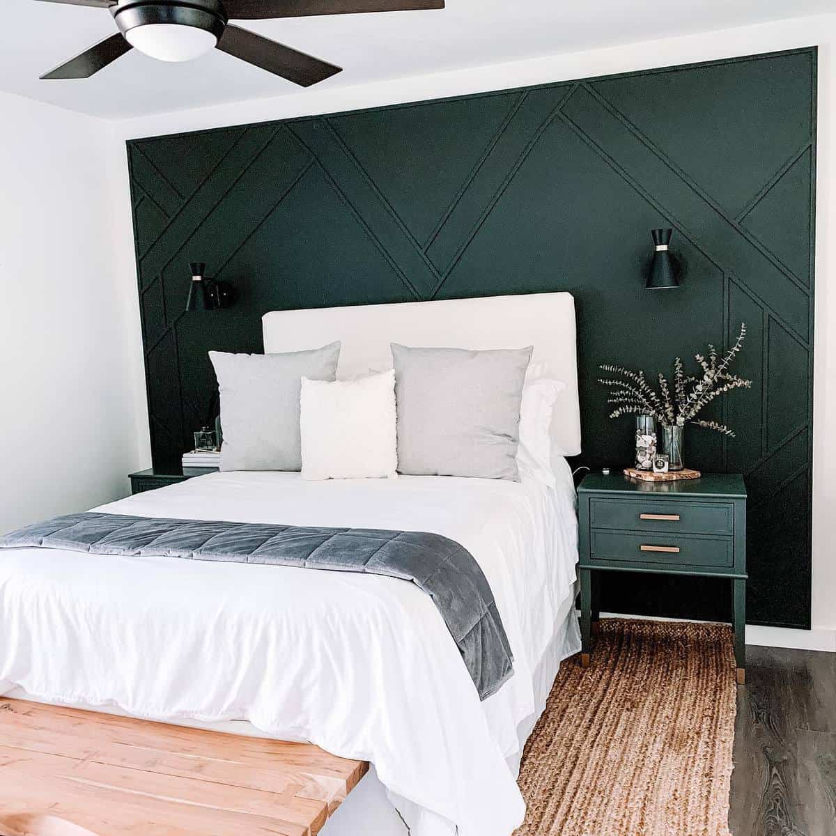 Modern bedroom with dark green accent wall, white bedding, gray pillows, bedside tables, and a ceiling fan