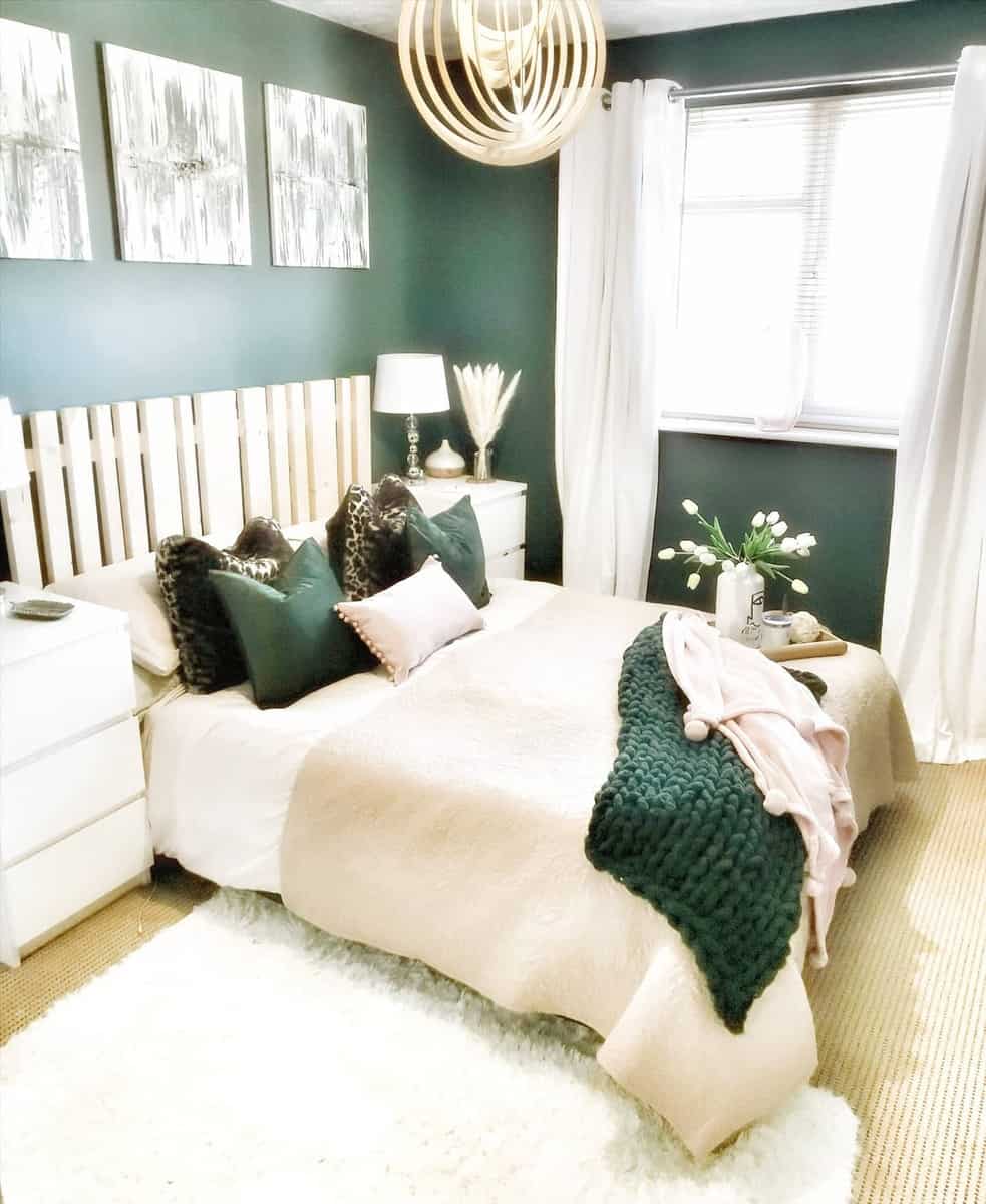 Cozy bedroom with green walls, modern decor, white bedding, green accents, and a large wooden pendant light