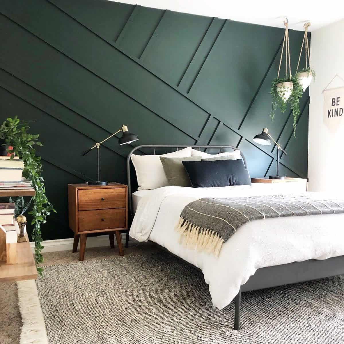 Modern bedroom with a geometric green accent wall, cozy bed, and plants, creating a serene and stylish atmosphere