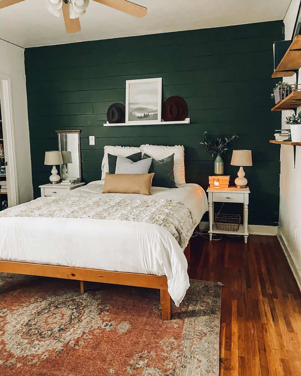 Cozy bedroom with a green accent wall, white bed, wooden floor, lamps on nightstands, and decorative pillows