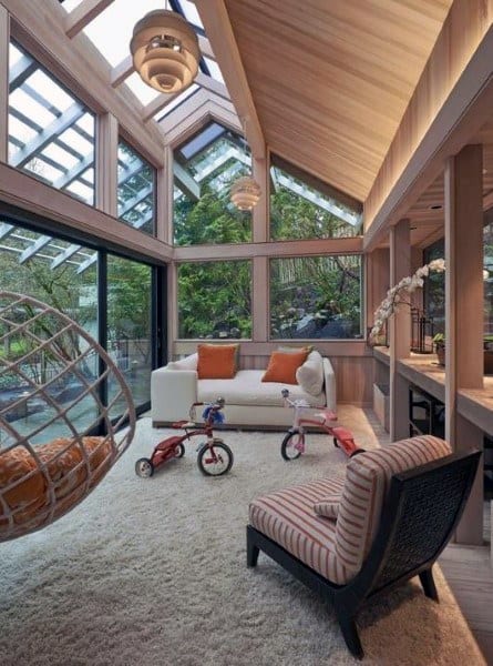 A modern sunroom with a wood and glass ceiling, cozy sofa, and stylish accent chair.