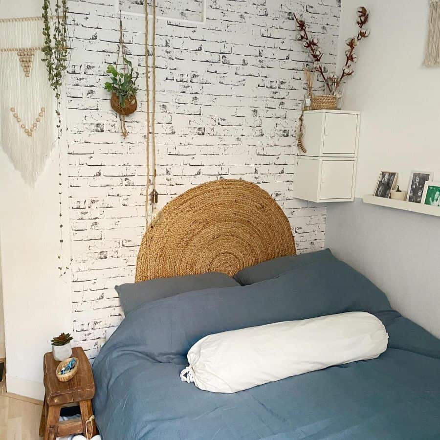 Cozy boho bedroom with a rustic brick accent wall, woven rattan headboard, and hanging plants for a natural touch.