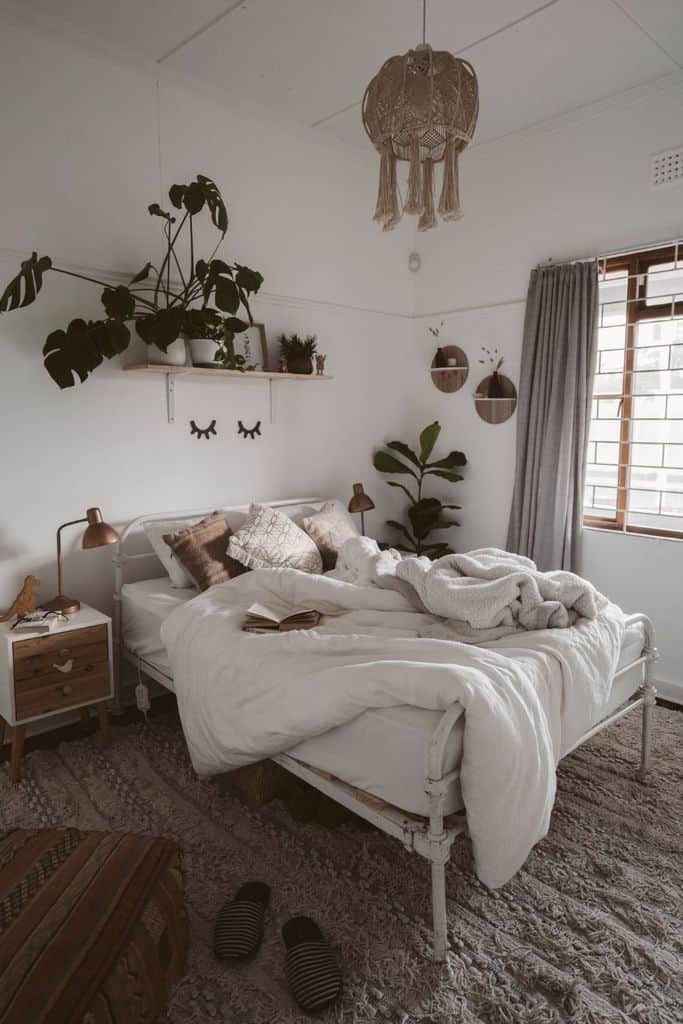 Minimalist boho bedroom featuring cozy bedding, hanging macramé light, lush greenery, and warm wooden accents.