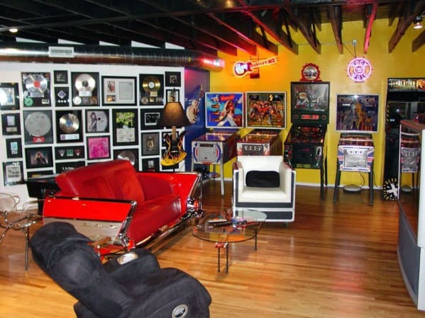 Retro-themed room with a red couch, arcade games, music memorabilia, and framed records on the walls