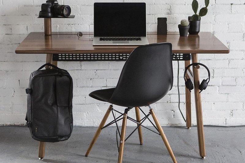 Modern workspace with wooden desk, black chair, laptop, and minimalist decor.