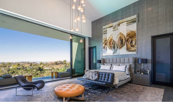 Luxury bedroom with floor-to-ceiling windows, abstract wall art, and a scenic balcony view.