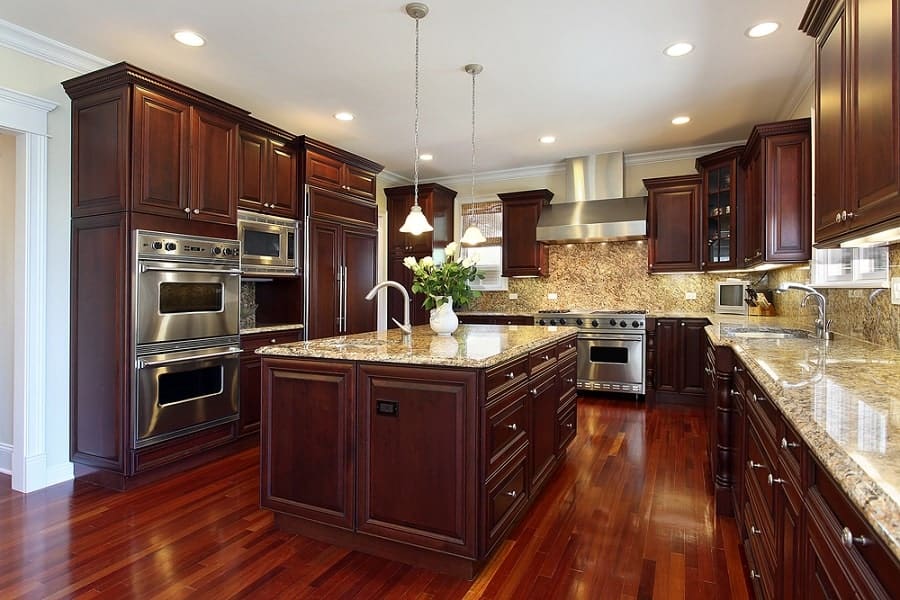 Modern kitchen with dark wood cabinets, granite countertops, stainless steel appliances, and a central island