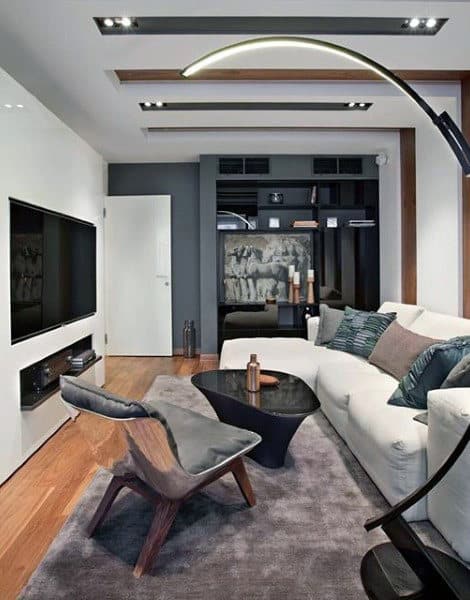 Modern living room featuring a white sofa, gray chair, black coffee table, large TV, and abstract artwork on the wall