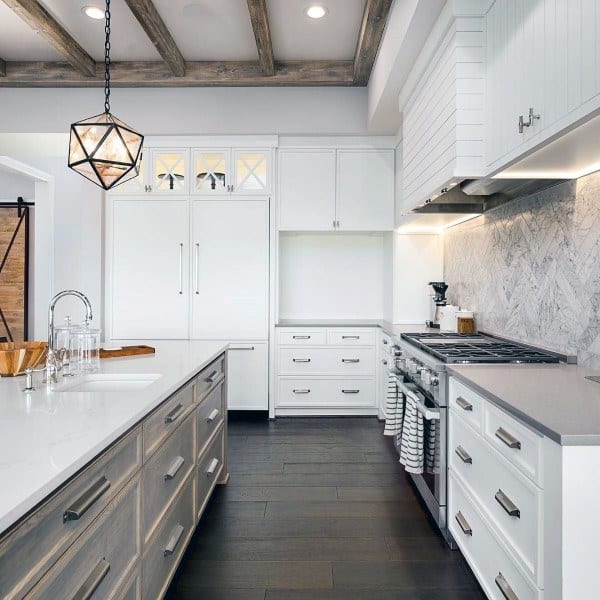 Bright kitchen with marble chevron backsplash, white cabinets, and rustic wood ceiling beams.