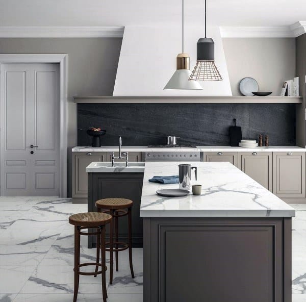 Dark stone backsplash contrasts beautifully with marble countertops and soft gray cabinets.