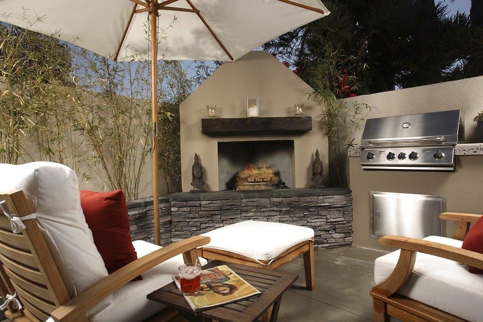 small corner patio with stone fireplace and bbq