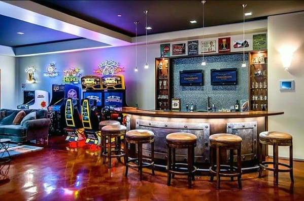 Home arcade room with a bar, vintage arcade games, bar stools, and colorful neon lights