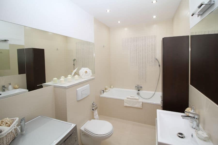 Spacious cream bathroom with bathtub, large mirror, and dark wood storage cabinets.