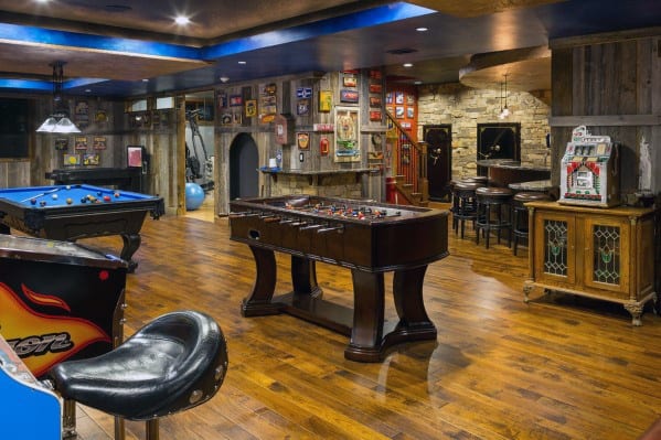 Game room with a pool table, foosball table, arcade machine, bar seating, and wooden floors