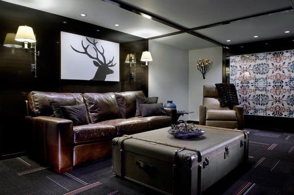 Midcentury modern mancave with leather sofa, vintage trunk coffee table, minimalist art, and cozy lighting.