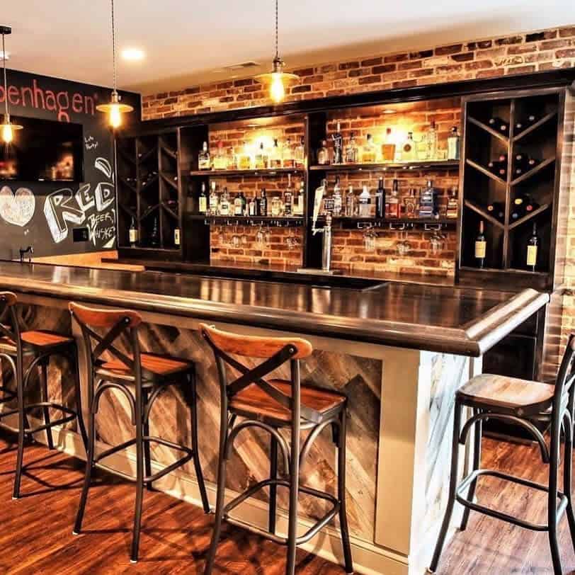 Brick basement bar with wood accents, wine racks, chalkboard wall, and warm pendant lighting.