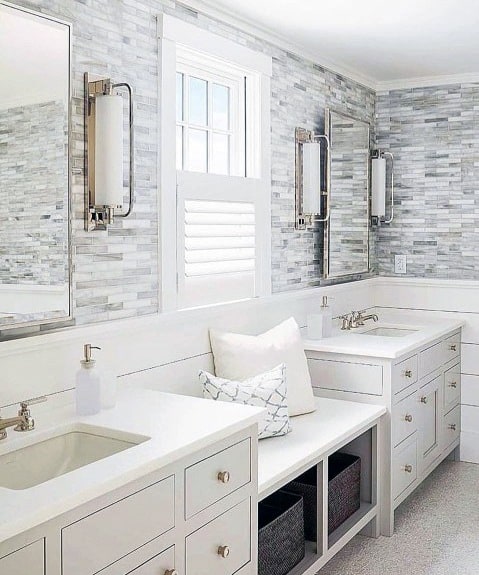 Bathroom with white vanity, marble backsplash, and large mirrors with wall sconces.