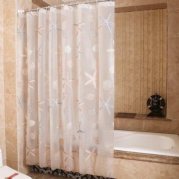 Beige shower curtain with seashell and starfish pattern in a tiled bathroom.