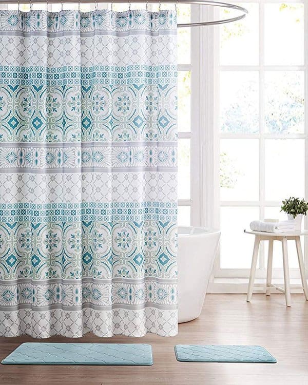 Blue and white patterned shower curtain in a bright bathroom with large windows.