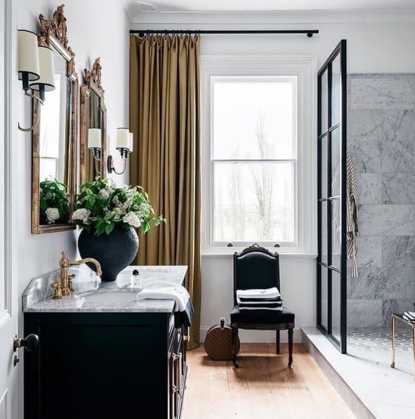 Elegant bathroom with gold curtains, marble vanity, and black accents.