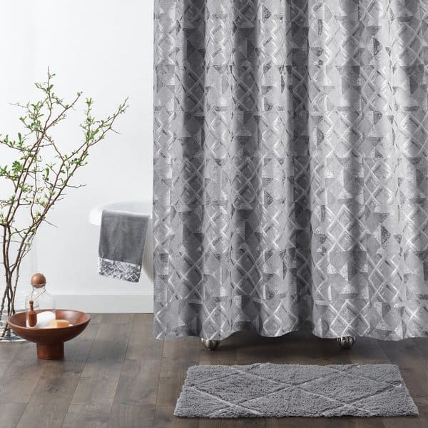 Gray patterned shower curtain with matching bathmat in a minimalist bathroom setting.