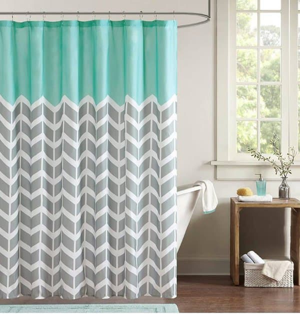 Aqua and gray chevron shower curtain in a bright bathroom with wooden accents.