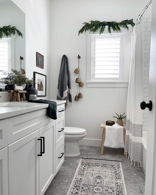 Minimalist bathroom with striped shower curtain, greenery accents, and decorative bells.