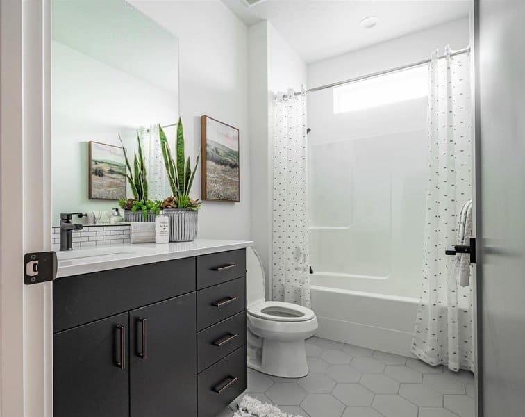 Modern bathroom with white dotted shower curtain, black vanity, and hexagonal floor tiles.