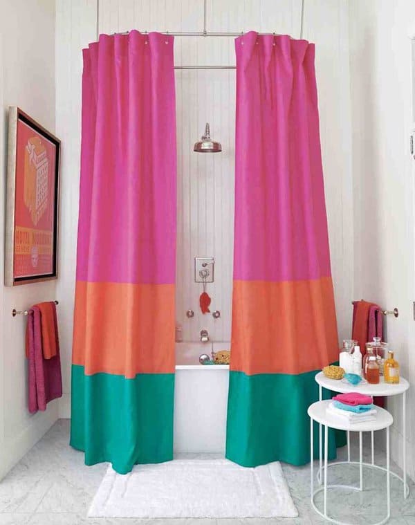 Colorful bathroom with bold pink, orange, and green shower curtains around a bathtub.