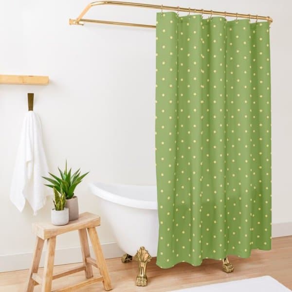 Green polka dot shower curtain in a minimalist bathroom with a clawfoot tub and small wooden stool.