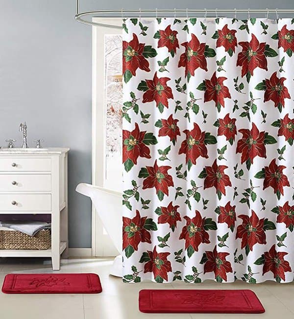 White shower curtain with red poinsettia print in a bright bathroom with matching red rugs.