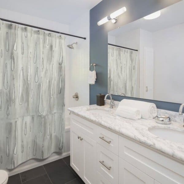 Light gray abstract patterned shower curtain in a modern bathroom with white vanity and marble countertop.