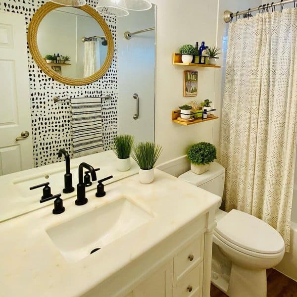 Small bathroom with patterned shower curtain, round mirror, floating shelves, and black fixtures.