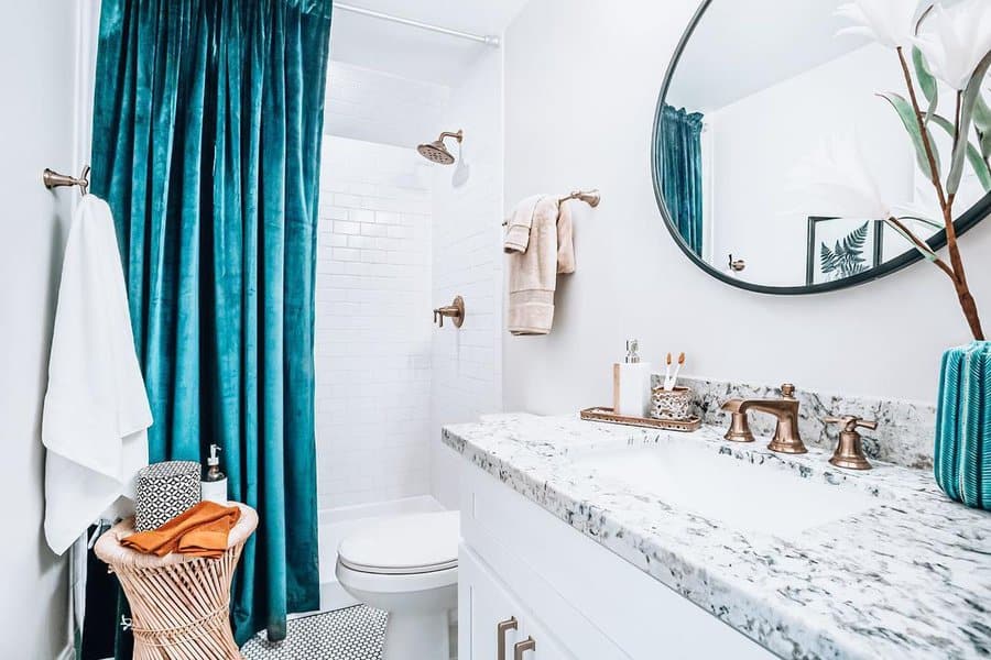 Small bathroom with a teal velvet shower curtain, granite countertop, and gold fixtures.