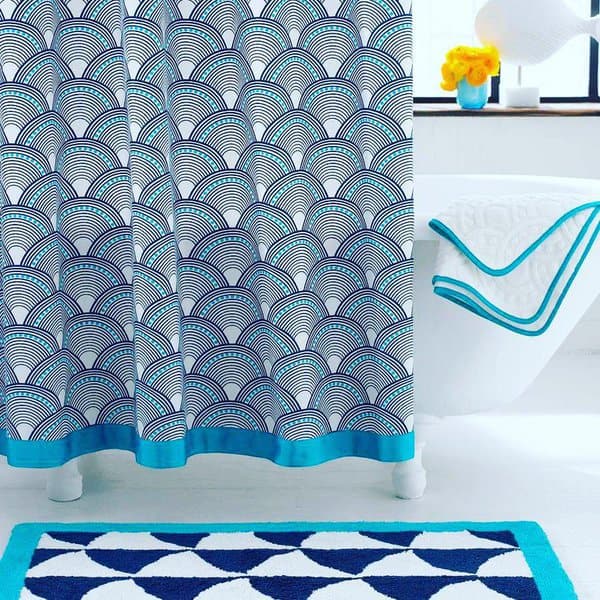 Blue and white wave-patterned shower curtain with matching bath mat in a modern bathroom.