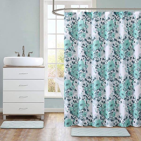 Floral-patterned shower curtain in soft teal and white tones in a bright bathroom.