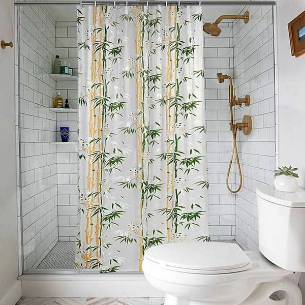 Bamboo-patterned shower curtain in a modern white subway tile bathroom with gold fixtures.