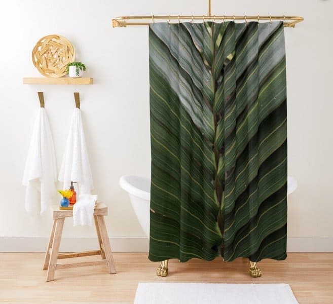 Tropical-themed shower curtain featuring a large green leaf design in a minimalist bathroom.