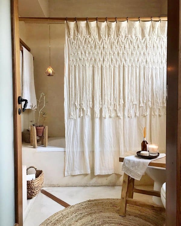 Boho-style bathroom with macramé shower curtain, wicker basket, and hanging light fixture.