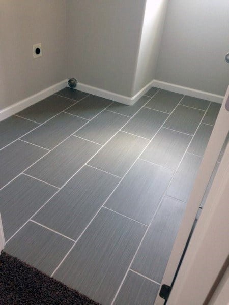 Bathroom with large grey rectangular floor tiles and white trim.