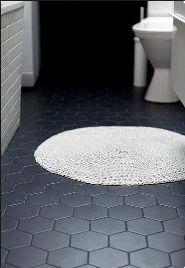 Bathroom with black hexagonal floor tiles and a small white round rug.