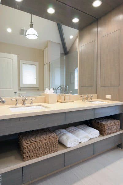 Modern bathroom with wall-to-wall vanity mirror, double sinks, and wicker basket storage.