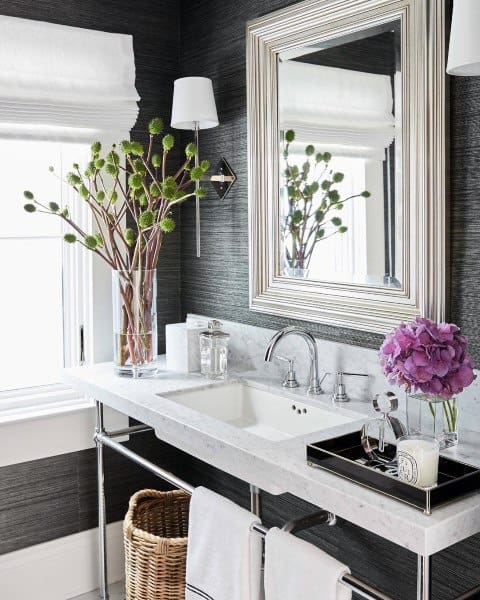 Bathroom with metallic-framed mirror, marble countertop, and modern floral decor.