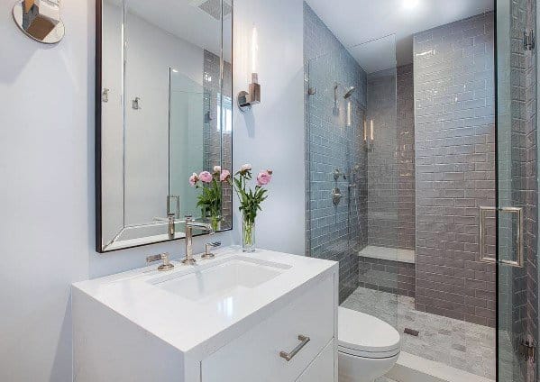 Modern bathroom with grey accents, white vanity, flowers, and glass shower enclosure