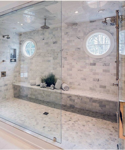 Luxurious marble-tiled shower with circular windows and built-in bench seating.