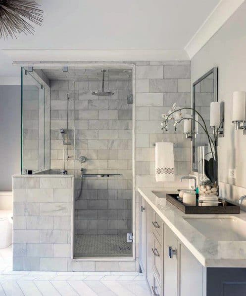 Modern bathroom with a marble-tiled shower and sleek white vanity with mirror.