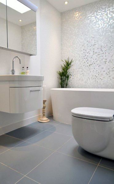 Modern bathroom with freestanding tub, glossy mosaic tile wall, and gray tiled floor.